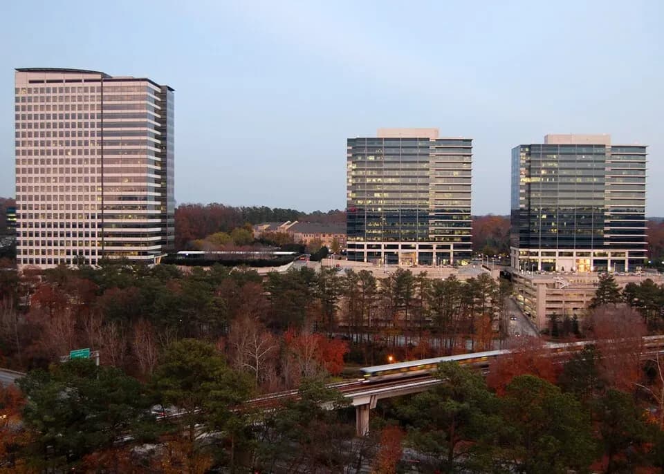 Modern office buildings and residential towers overlooking wooded area with highway overpass